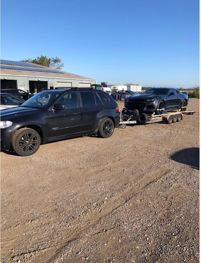 Black SUV transporting a sports car on a trailer
